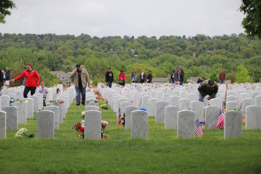People wander the headstones at Fort Logan National Cemetery.